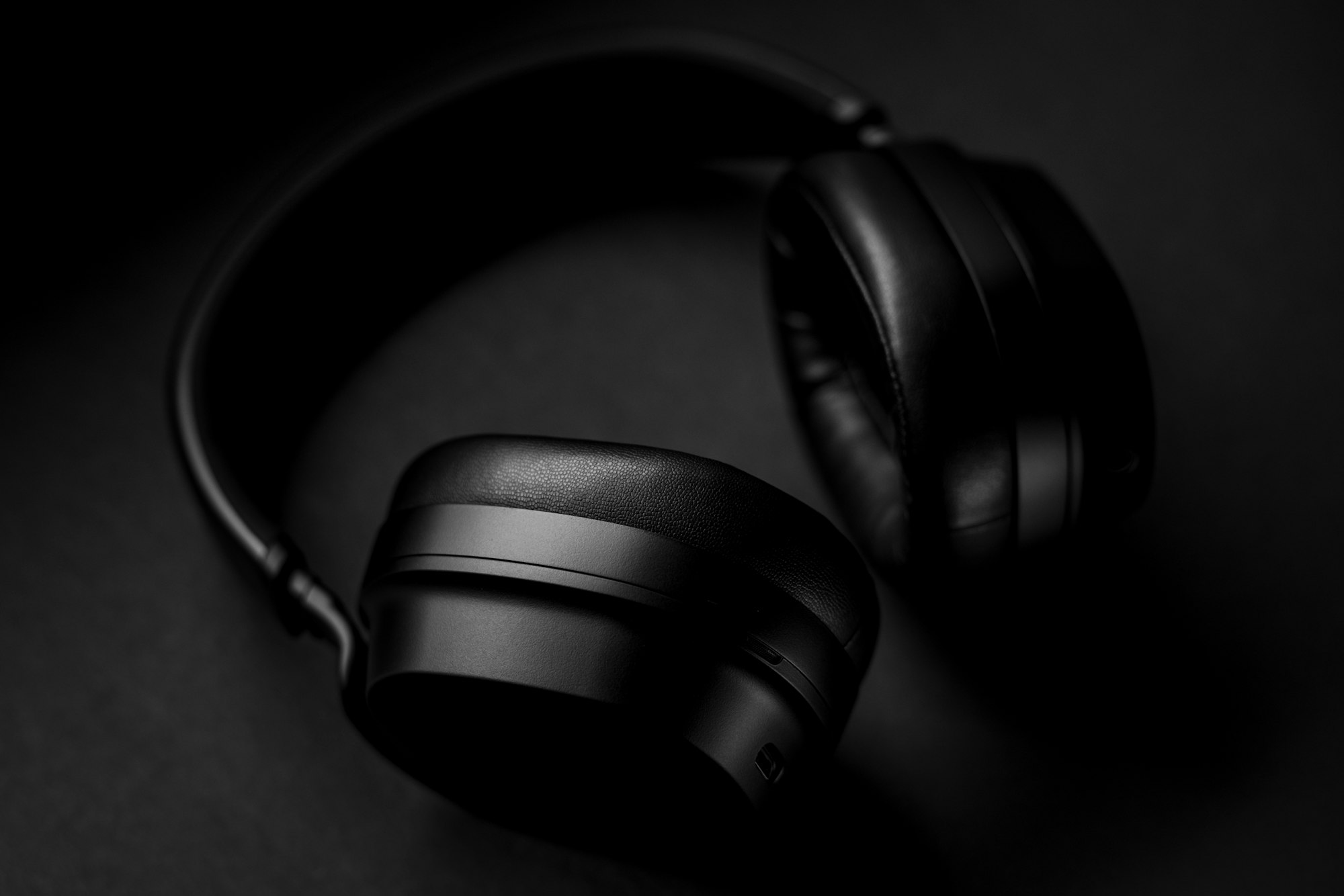 Black headphones on a table, close crop of the ear cup